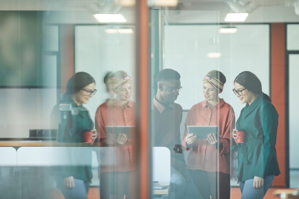 Young Team Behind Glass in Modern Office